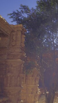 The scene shows old stone structures surrounded by greenery. Sunlight shines on the ruins, and trees stand nearby. The sky is bright and clear this time of day, adding to the view.