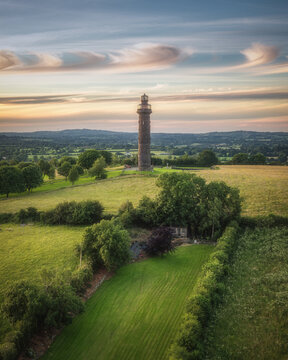 Aerial view of the historic Spire of Lloyd stone tower surrounded by lush green fields and rolling countryside in County Meath, Ireland.