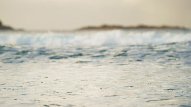 Low angle ocean foam and waves near distant rocky island
