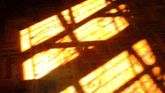 Golden sunlight streams through window panes onto wooden floorboards
