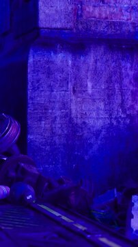 Construction debris lies in an alley illuminated by blue light. The scene shows discarded materials against a textured wall. Shadows create an atmosphere of depth and mystery.