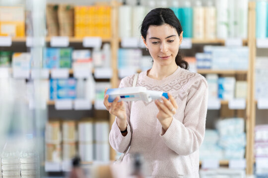 Girl in autumn clothes buys medicinal ointment or gel at a pharmacy
