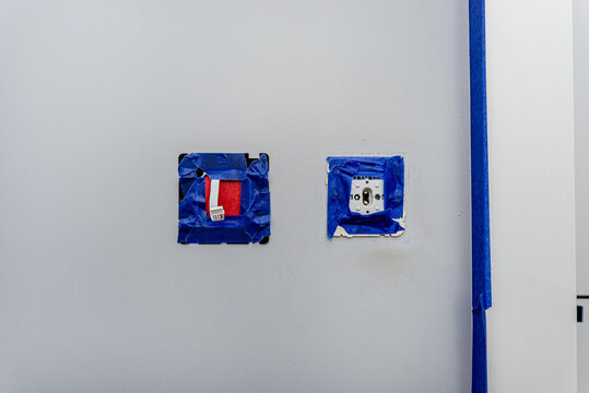 Renovating wall with electrical outlets and blue painter's tape
