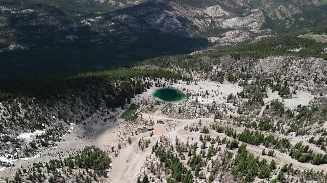 Sunny Summer Drone Flight Over Turquoise Mountain Lake with Snow and Pine Trees