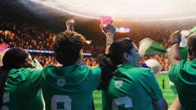 Close up of football supporter holding drink cups and fan props in stadium stands, showing crowd doing energetic chanting, holding beverages, concept of match day stadium experience.