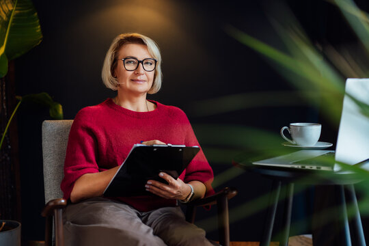 Professional Psychotherapy. Successful female Psychologist Smiling To Camera Sitting On armchair In Office. Mature 50s middle-age professional portrait of teacher, coach, mentor, therapist, counselor