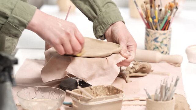 4k video capturing the refinement process of a clay artwork. Artisan hand uses a sponge to carefully clean and shape the edges of a slab, demonstrating the attention to detail required in ceramics