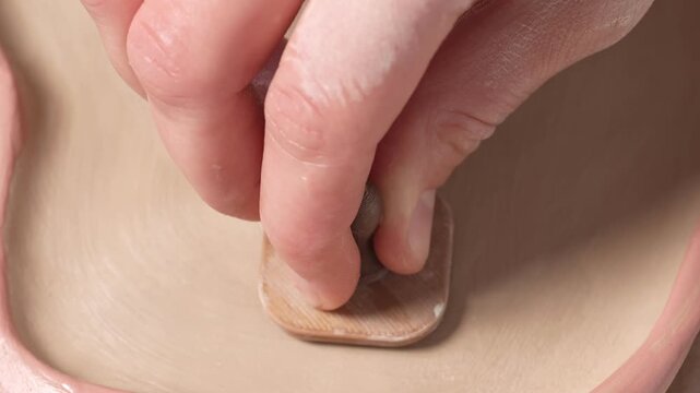 4k close-up of an artisan stamping a clay vessel. Artisan marks a handcrafted ceramic piece with a custom signature stamp, adding branding and authenticity