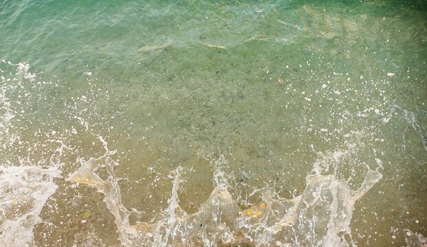 Turquoise sea surface with crushing waves and foam colorful water ariel shot summer sea background