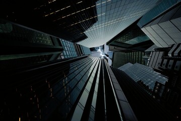 Dramatic low angle worm eye view looking up at modern glass skyscrapers converging toward dark moody sky in financial district © Ahmed