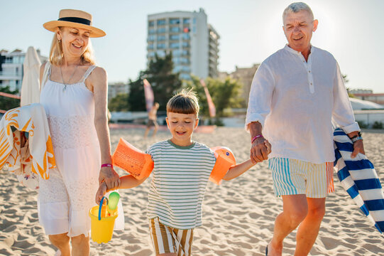 Grandparents Running Along Beach With Grandchildren On Summer Vacation