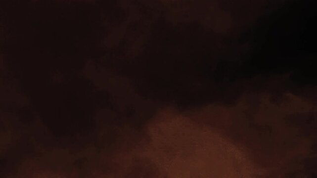 Stormy Domesday Halloween Night 4K Loop features rolling dark clouds and blowing smoke with flashes of lightning with a red/orange tint in a loop.