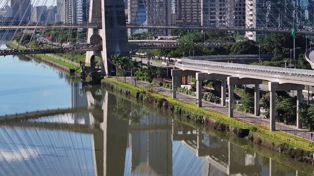 Close aerial view of the Pinheiros River with metro line, bike path and urban infrastructure in S&atilde;o Paulo, Brazil.