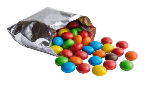 Isolated vibrant candy coated chocolates spilling from metallic silver foil bag