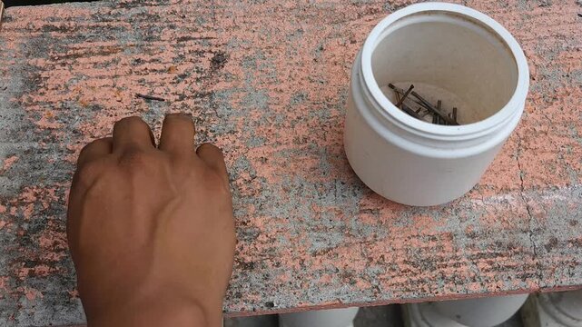 Hand placing welding slag and metal residue into a white container
