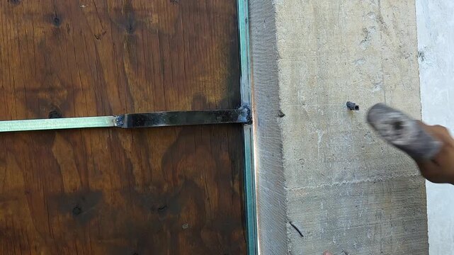 Hammering a plastic wall plug anchor into a concrete column with a mallet