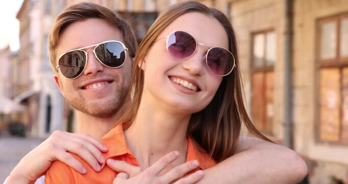 Lovely couple in sunglasses on city street, camera moving in