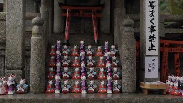 Kitsune fox figurines lined on stone steps at Fushimi Inari Shrine in Kyoto Japan