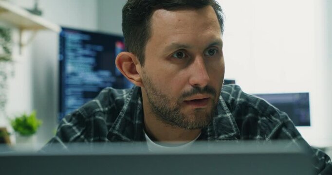Caucasian programmer typing and analyzing code at workstation.Developer inspects software, debugs applications and secures networks to support enterprise systems and innovation in an indoor office env