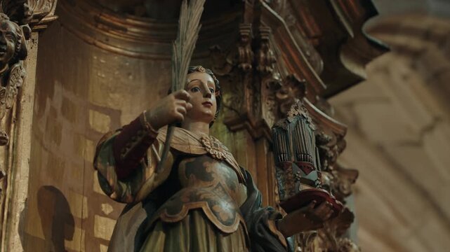 Carved polychrome statue of Saint Cecilia holding a pipe organ on a gilded baroque altar