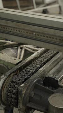 Greasy roller chain runs over a sprocket on an industrial machine drive with a measuring scale