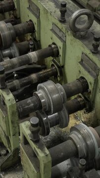 Rows of steel forming rollers on shafts of an industrial roll forming machine in a metal workshop