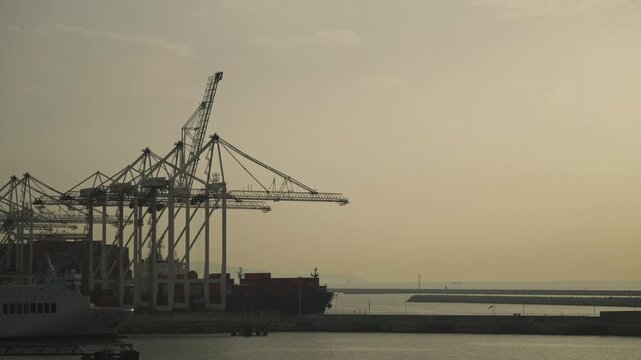 Large port cranes and cargo ship with containers at dusk in Tangier harbor Morocco