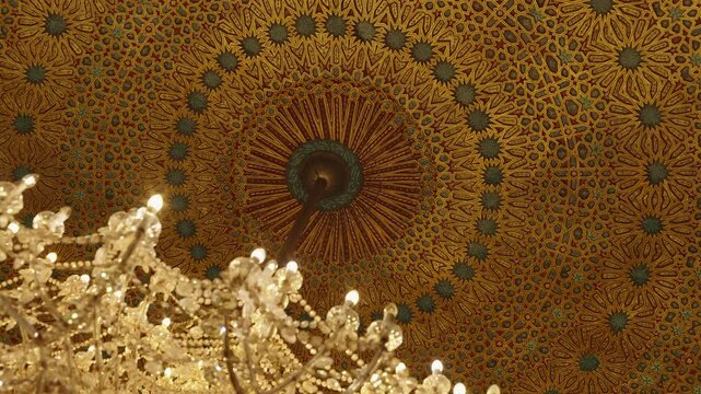 Decorated Moroccan dome ceiling with golden arabesque pattern and crystal chandelier