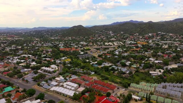 Sweeping aerial panorama of Windhoek spreading across a valley surrounded by the Khomas Highland mountains. A sprawling capital ringed by highland mountains.