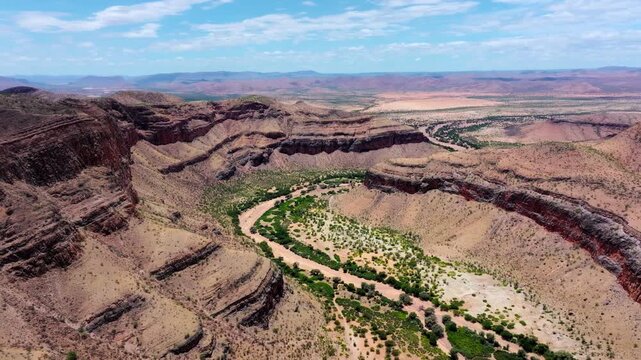 Drone footage over a meandering green riverbed carving through rugged canyon terrain in the Namib-Naukluft, central Namibia, classic incised meanders.