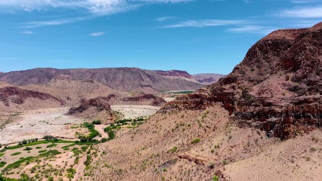 Aerial view of rugged rocky koppies and granite outcrops rising from a vast desert plain in central Namibia under a bright clear sky.
