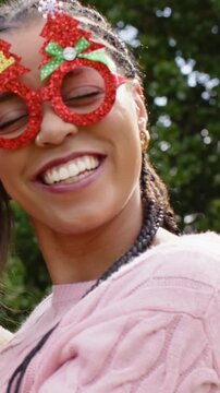 Vertical video: Smiling duo in pink knit taking selfie as camera pulling in park with red glasses