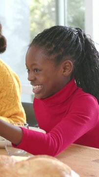 Vertical video: Laughing child in red sweater reaching after adult offering bread to eat at home
