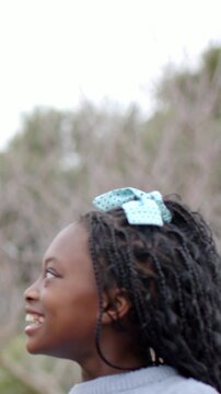 Vertical video: Calling sister nudging kid laughing looking up in park with blue jumper, copy space