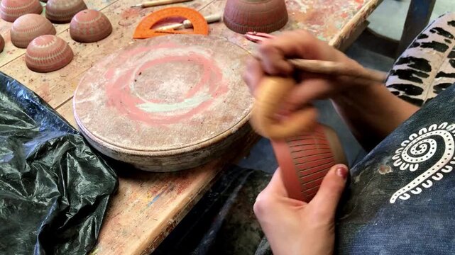 Close up view of an artisan engraving decorative patterns into clay pottery by hand, showcasing traditional ceramic craftsmanship in Oaxaca, Mexico