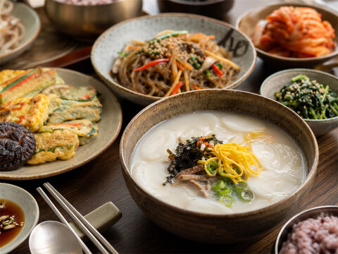 Traditional korean meal with rice porridge colorful side dishes kimchi pancakes seaweed greens and chopsticks on a wooden table creating a cozy healthy dining scene with authentic flavors