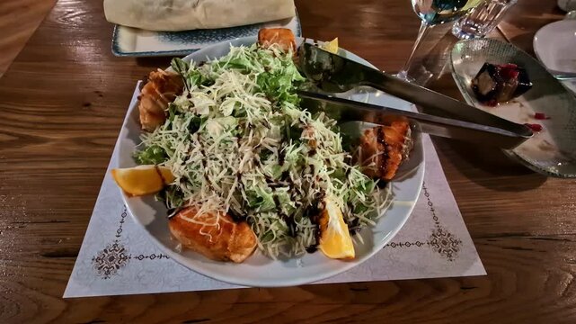 Grilled salmon caesar salad served with parmesan cheese and lemon in a restaurant
