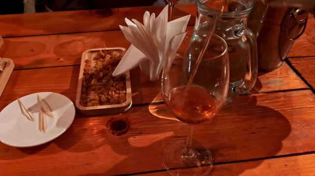 Rich amber-colored wine being poured into a tasting glass on a rustic wooden table in Georgia