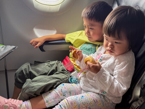 Brother and sister eating pastry on airplane during flight