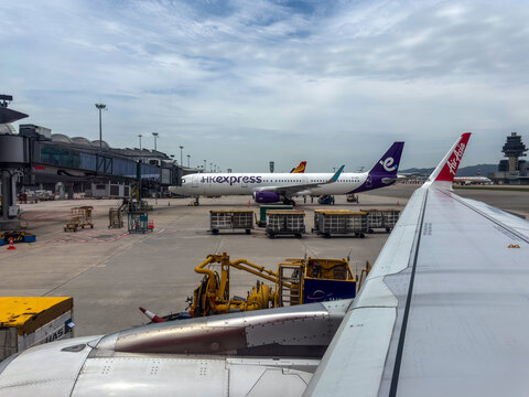 Airplane wing at airport with other airplanes parked on tarmac