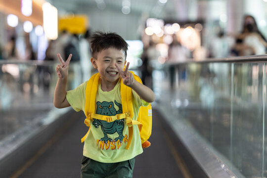 Little boy running on moving walkway in airport terminal