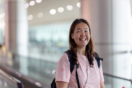 Tourist smiling in airport terminal with backpack ready for vacation