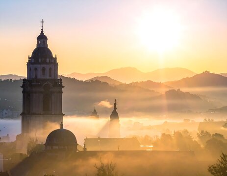 A serene morning scene of a historic town shrouded in fog at sunrise