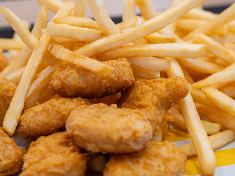 Macro photograph of a popular fast food combo meal, featuring golden, crispy French fries and breaded chicken nuggets.