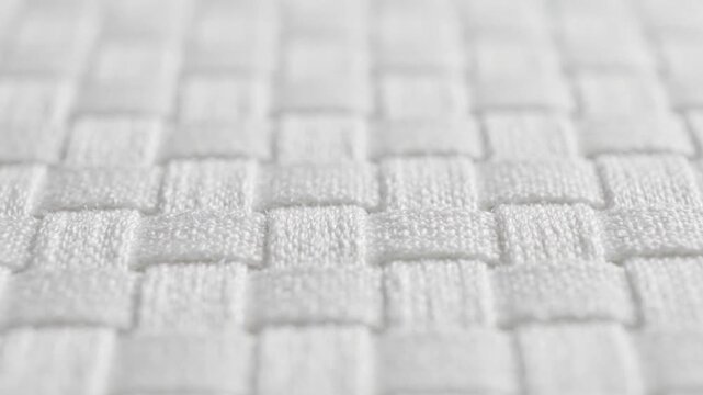 Closeup of textured white fabric with a woven pattern on a white background