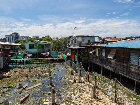 Stilt houses in Sembulan water village, Kota Kinabalu, Sabah, with the city skyline in the background.