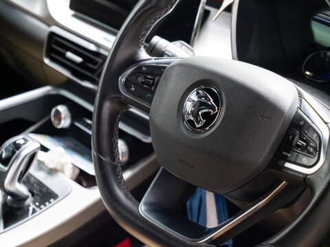 Close-up of a car dashboard, highlighting the steering wheel, infotainment screen, and center console