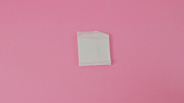 Flat lay stop motion of menstrual pads moving on pink surface