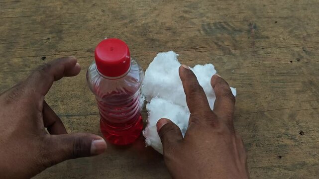 Hand placing a small protective oil bottle and cotton on an mdf board