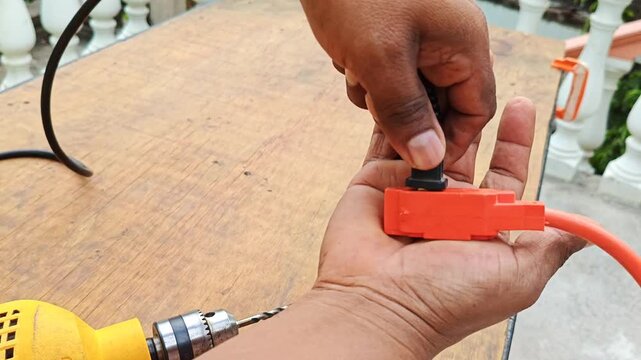 Hand plugging a drill electrical plug into an extension cord wire
